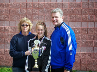 Molly Curry posing with her parents holding the State Cup trophy for soccer.