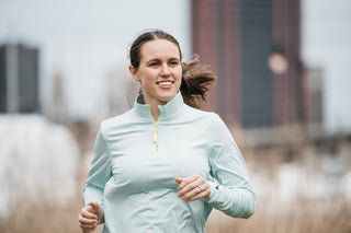 Molly Curry running and smiling in Middle Trail quarter zip.