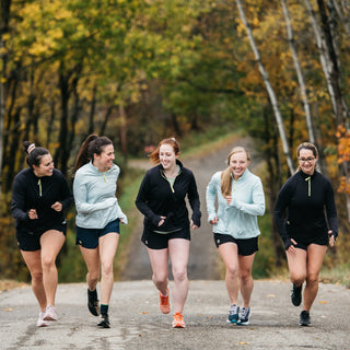 A group of women running up a hill in the fall in Middle Trail running apparel