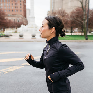 Woman running on a city street with buildings and trees in the background