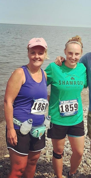 Jackie Goergen posing with Genny Goergen after a race in front of water.