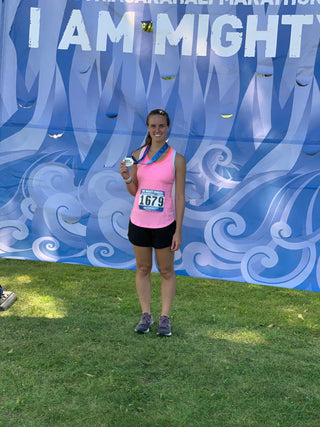 Molly Curry posing with her half marathon medal after the race.