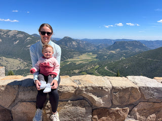 Molly Curry posing on a mountain side with her baby daughter.