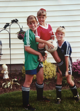 Molly Curry with her two sisters posing with a soccer ball.