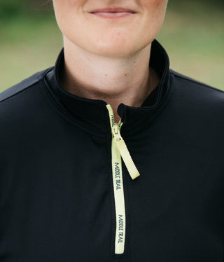 A close-up picture of someone wearing the black women's quarter-zip with the zipper fully raised to show how the collar stands up.