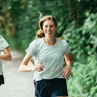 woman running in light blue tee and blue shorts