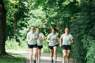Welcome to Middle Trail Women's Running Club. A group of four women running together down a gravel trail in Middle Trail running apparel. 