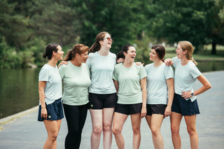 A group of 6 women all laughing together on a running path in Buffalo, NY wearing Middle Trail women's running apparel. 