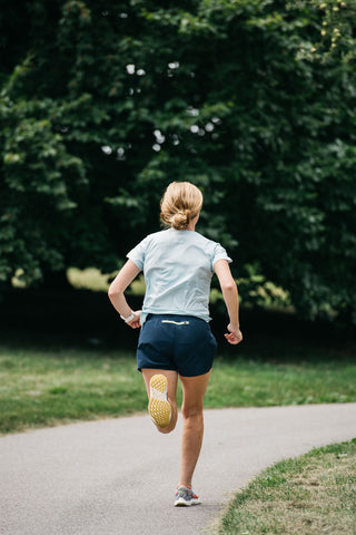 A women running away of the camera down a path in the blue women's running shorts.